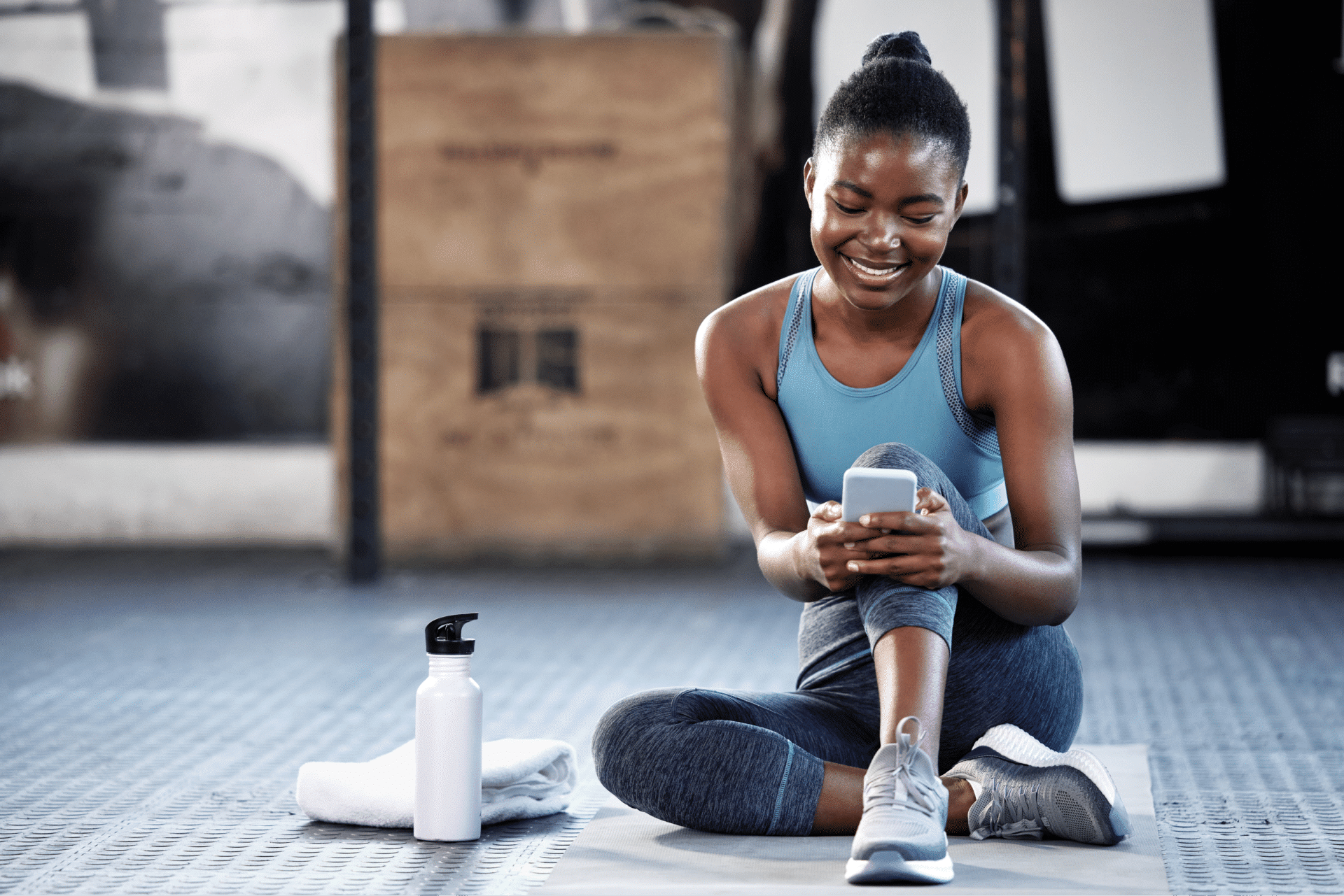 Clubwise | Woman in gym looking at phone smiling